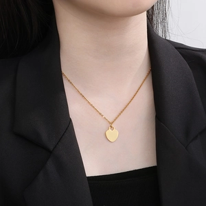 Sweet golden heart pendant necklace in titanium steel on model's neck, minimalist style