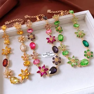 Detailed macro view of four colorful floral crystal necklaces on white velvet padding