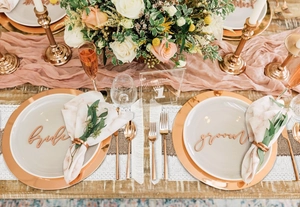 Detail of rose gold charger plates with Bride and Groom decorative signs for wedding table