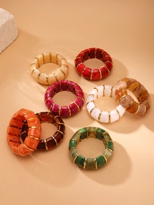 Close-up of colorful marbled resin blocks with 18k gold-plated metal spacers on elastic bracelets