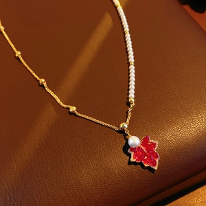 Détail du pendentif feuille d'érable rouge sur collier de perles plaqué or 18K