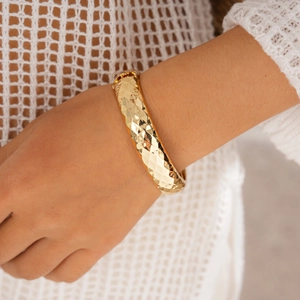 Nahaufnahme des goldenen geometrischen Armbands mit Rautenmuster am Handgelenk