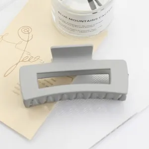 Detail of light grey matte rectangular hair claw clip with a hollow design and sturdy spring