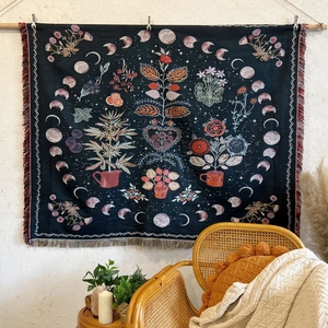 Detail of bohemian moon phase and floral woven tapestry with red and white tassels