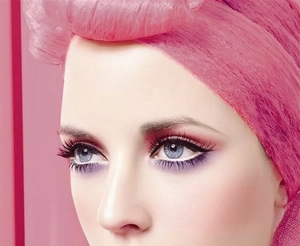 Close-up of vibrant pink and purple eye makeup with artistic headpiece styling