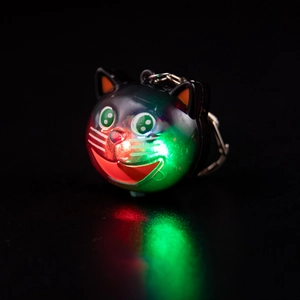 Glow-in-the-dark owl keychain with red and green LED lights on a black background