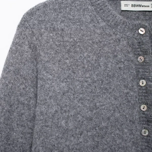 Grey knit cardigan for women with ruffled trim and pearlescent buttons on white background