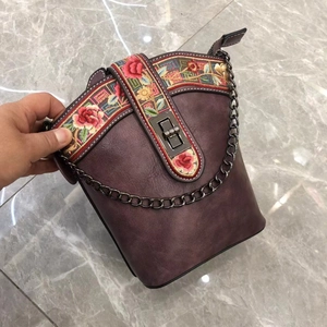 Detail of hand-held purple PU leather bucket bag with ethnic embroidery and metal clasp