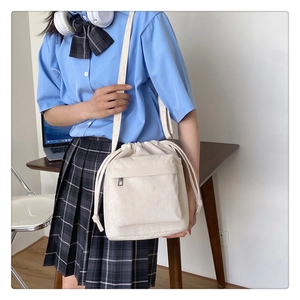 Close-up of white corduroy drawstring crossbody bag worn by model in a daily scene