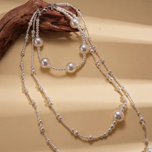 Détail d'un collier de perles baroques multicouche sur bois vintage et tissu beige