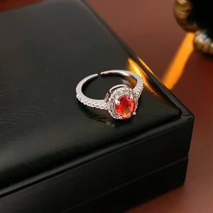 Macro view of adjustable silver ring with orange oval gemstone and sparkling zircon halo