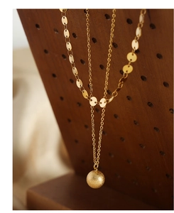 Detail of gold-plated double-layer necklace with frosted spherical pendant and disc chain