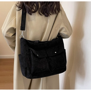 Close-up of black corduroy tote bag featuring two large front pockets with metal snaps