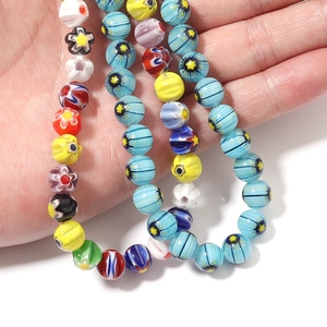Macro shot of colorful Millefiori glass beads with floral patterns held in a hand