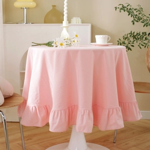 Pink round tablecloth with ruffled edges on a table in a cozy home setting with flowers
