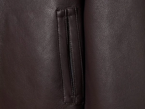 Macro shot of dark brown faux leather jacket texture and high-density stitching detail