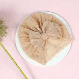 Detail of baby lace turban in beige featuring a large mesh bow and breathable fabric