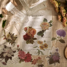 Flat lay of vintage floral scrapbook papers with lace and dried flowers backdrop