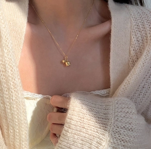 Close-up of elegant gold tulip lily of the valley pendant necklace worn by a model