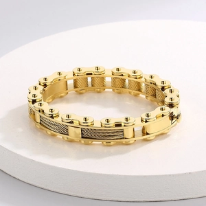 Detail of gold-plated bicycle chain bracelet featuring knurled texture and steel cables