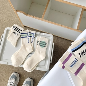 Chaussettes blanches en coton avec rayures et slogan sur un fond de tapis blanc