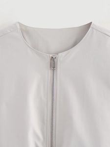 Detailed view of the round neckline and silver metal zipper on a light gray bomber jacket