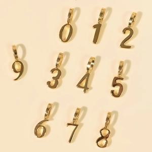 Flat lay of polished 18K gold plated number charms from zero to nine for DIY necklaces