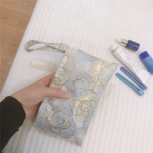 Close-up of blue rose jacquard canvas mini handbag with golden floral patterns