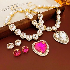 Macro view of gold-tone jewelry set with round clear stones and heart pendants