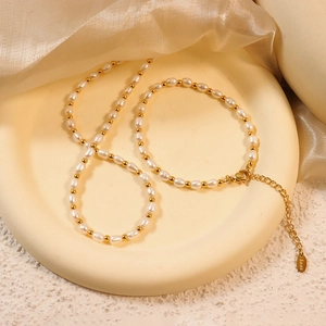 Elegant Baroque pearl necklace and bracelet set with gold beads on a beige tray