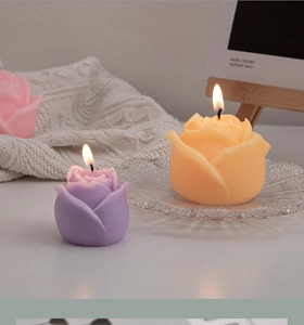 Close-up of burning rose-shaped scented candles in purple, orange, and pink colors