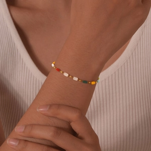 Detail of bohemian gold beaded bracelet with colorful stones worn on a female wrist