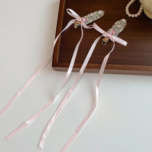 Detail of pink silk ribbon bow hair clips with shimmering crystals and pearls on wood