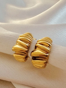 Macro shot of 18k gold croissant hoop earrings with thick pleated texture and mirror finish