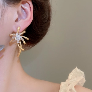 Detail view of golden firework drop earrings with zircon crystals worn on a female model
