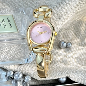 Detailed close-up of a horseshoe-shaped gold watch with a pink dial on linen background