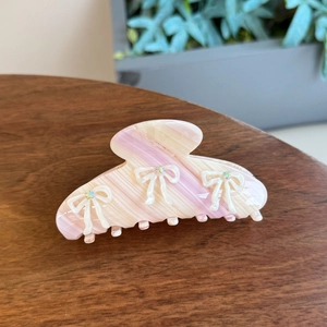 Pink marble acetate bow hair claw clip with crystal rhinestones on a wooden surface