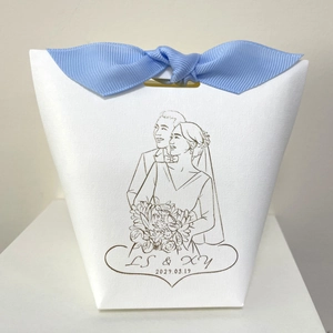 Detailed view of white wedding gift box with blue ribbon and custom couple line illustration
