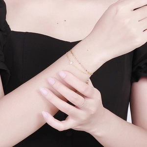 Elegante bracciale dorato a strati con piccoli diamanti bianchi al polso femminile