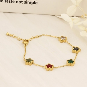 Detail of 18K gold plated bracelet with five colorful star charms on white fabric