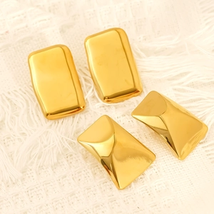 Deux paires de boucles d'oreilles carrées en acier doré sur un fond en maille beige