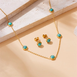 Vintage gold necklace and earrings set with round turquoise stones on stone decor