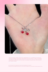 Dettaglio macro della collana con ciondolo a ciliegia e fiocco in argento lucido