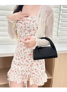 Detailed view of black lychee pattern handbag with elegant gold chain strap on model