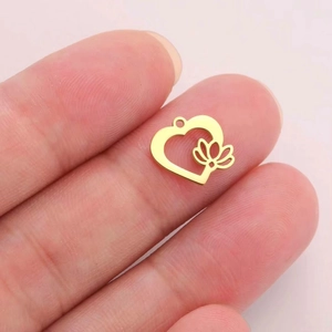 Miniature gold stainless steel heart-shaped lotus pendant held on a fingertip for DIY jewelry