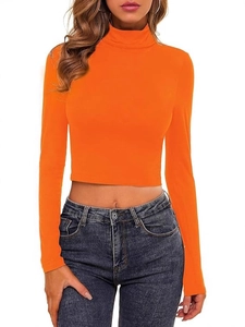 Orange long sleeve turtleneck crop top styled with dark denim jeans on white background
