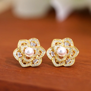 Detailed macro view of gold flower earrings with pavé crystals and central pearl inlay