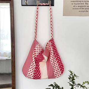 Detailed view of a red polka dot canvas tote bag hanging in a minimalist interior setting