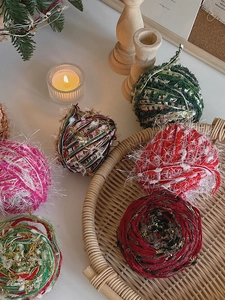 Close-up of DIY mixed yarn Christmas ornaments with tinsel and soft pom-poms on a tray