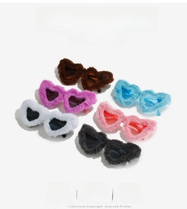Detailed view of six colorful plush heart-shaped party sunglasses on a white stand
